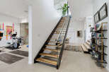 Discover a modern and spacious home featuring a dedicated home gym area with cardio equipment and yoga mats.