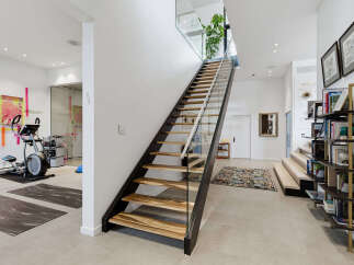 Discover a modern and spacious home featuring a dedicated home gym area with cardio equipment and yoga mats.
