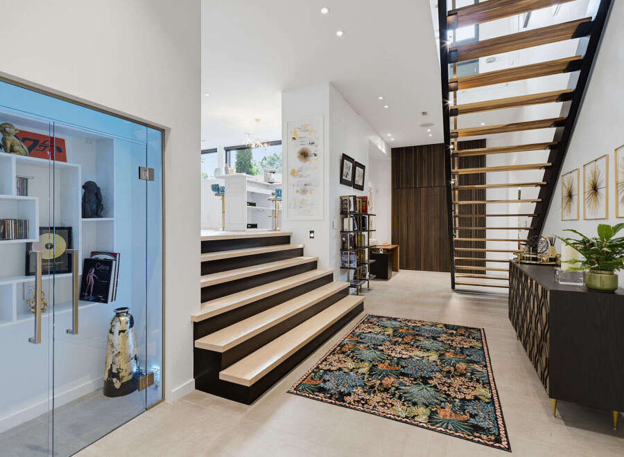 Step into a modern entryway featuring a floating staircase with wooden treads and a sleek black metal frame.