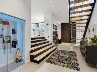 Step into a modern entryway featuring a floating staircase with wooden treads and a sleek black metal frame.