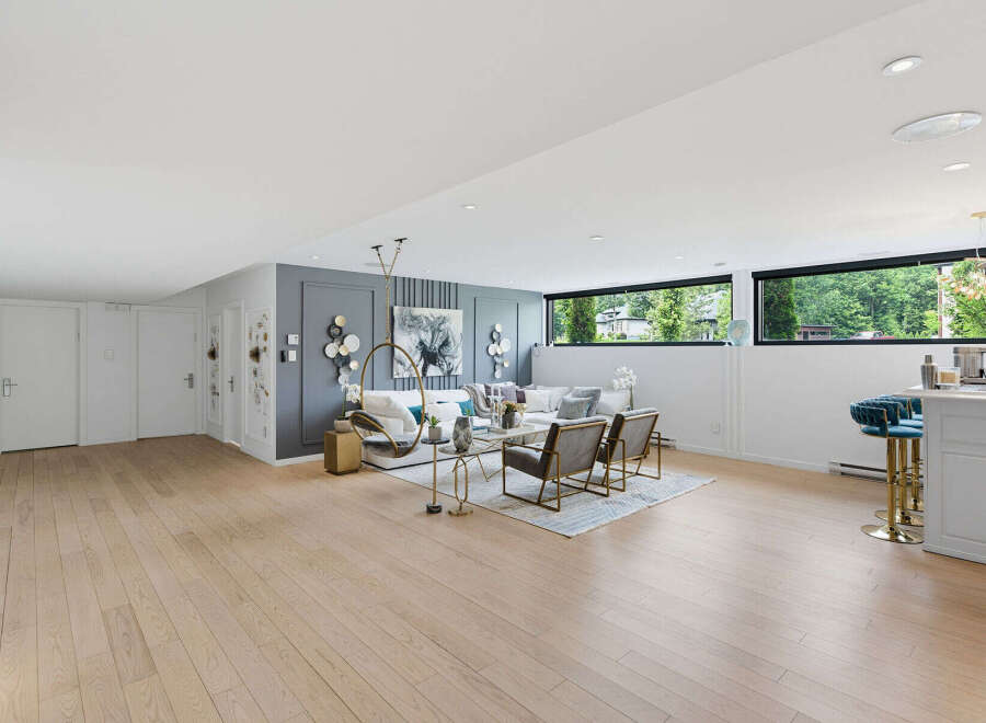 Experience modern living in this spacious basement suite, featuring a stylish living area with a comfortable sectional sofa and accent chairs, perfect for relaxation and entertainment.