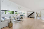 Experience modern living in this spacious basement suite, featuring a comfortable white sectional sofa and a unique hanging chair for ultimate relaxation.