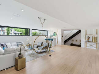 Experience modern living in this spacious basement suite, featuring a comfortable white sectional sofa and a unique hanging chair for ultimate relaxation.
