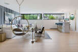 Experience modern living in this spacious open-concept living area, featuring a stylish white bar with plush blue stools and a unique hanging chair.