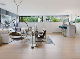 Experience modern living in this spacious open-concept living area, featuring a stylish white bar with plush blue stools and a unique hanging chair.