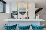Experience luxury and entertainment in this stunning home bar area, featuring plush velvet bar stools and a sleek white countertop perfect for hosting.