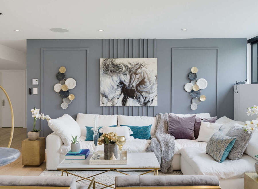 Experience modern luxury in this stunning living room, featuring a plush white sectional sofa adorned with elegant throw pillows and a cozy blanket.