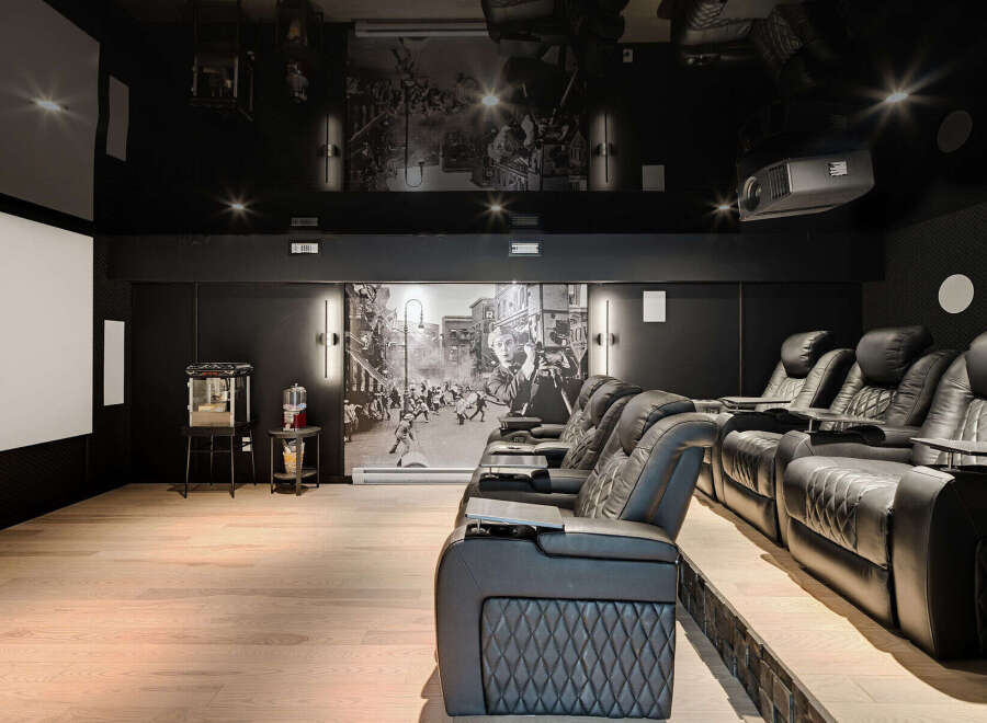 Experience ultimate cinematic luxury in this state-of-the-art home theater, featuring plush reclining seats with built-in cup holders and tray tables.