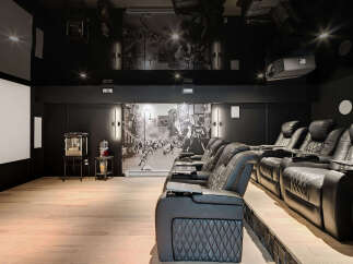Experience ultimate cinematic luxury in this state-of-the-art home theater, featuring plush reclining seats with built-in cup holders and tray tables.