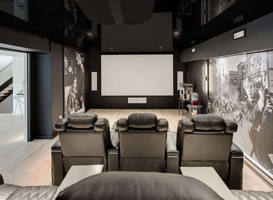 Experience ultimate entertainment in this luxurious home theater, featuring plush leather recliners and a large projection screen for an immersive viewing experience.