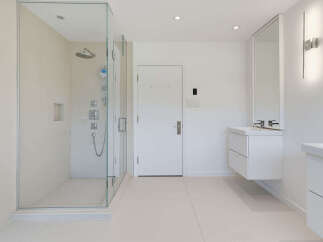 Experience modern luxury in this spacious bathroom, featuring a sleek glass-enclosed walk-in shower with multiple shower heads for a spa-like experience.