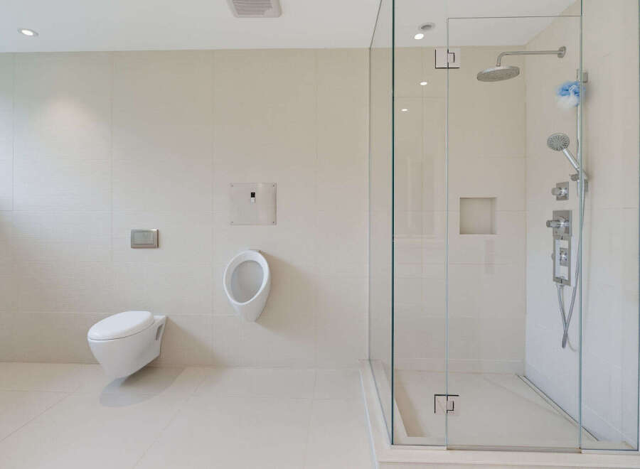 Experience modern luxury in this spacious bathroom featuring a sleek wall-mounted toilet and a sophisticated urinal.