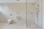 Experience modern luxury in this spacious bathroom featuring a sleek wall-mounted toilet and a sophisticated urinal.