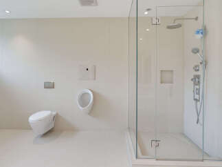 Experience modern luxury in this spacious bathroom featuring a sleek wall-mounted toilet and a sophisticated urinal.