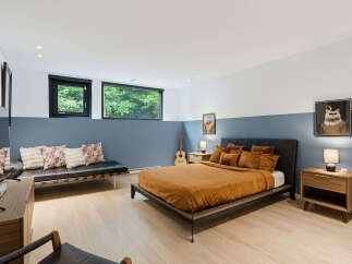 Experience modern comfort in this stylish bedroom, featuring a plush orange duvet on a sleek platform bed.
