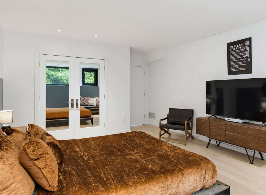 Experience modern comfort in this stylish bedroom, featuring a plush velvet bed and a sleek entertainment center with a large flat-screen TV.