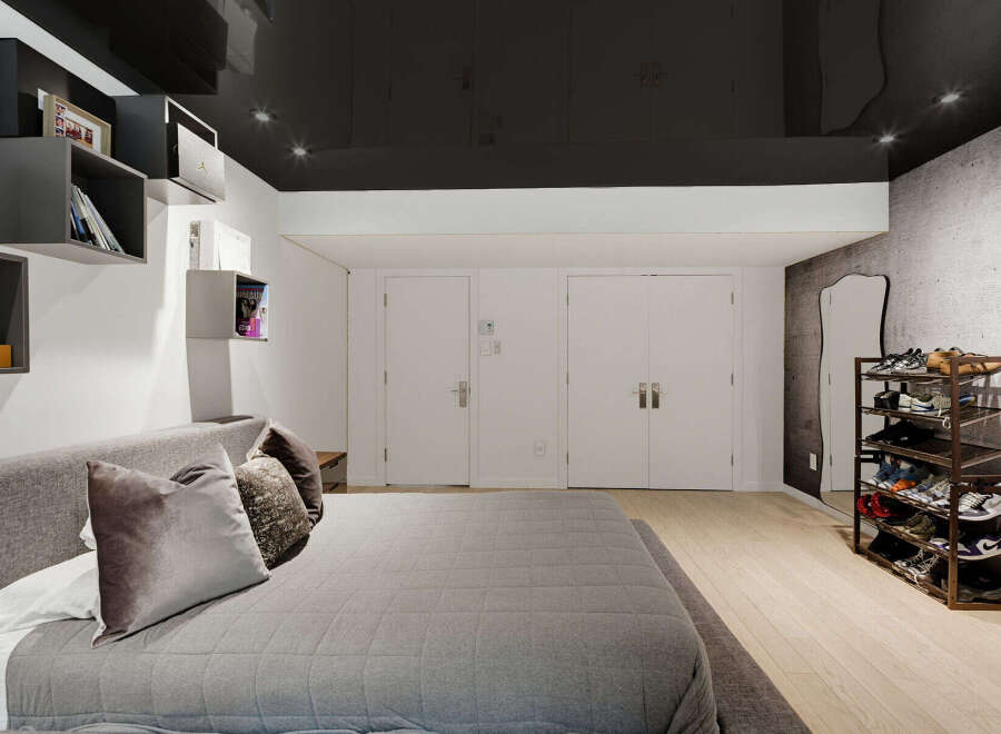 Discover modern living in this stylish bedroom featuring a sleek, dark ceiling and integrated shelving for a minimalist aesthetic.