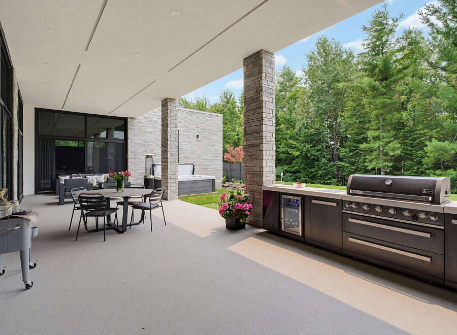 Experience luxurious outdoor living with this expansive patio featuring a built-in grill, beverage cooler, and comfortable dining area.