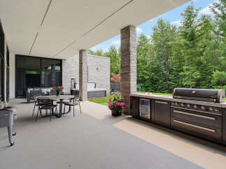 Experience luxurious outdoor living with this expansive patio featuring a built-in grill, beverage cooler, and comfortable dining area.