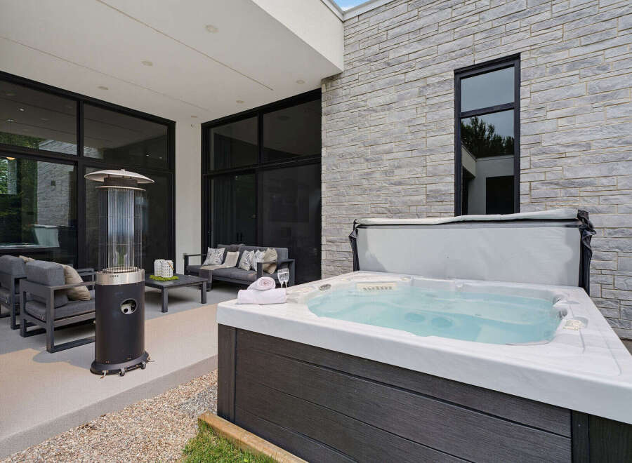 Experience luxury outdoor living with this stunning patio featuring a modern hot tub perfect for relaxation.