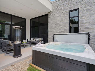 Experience luxury outdoor living with this stunning patio featuring a modern hot tub perfect for relaxation.