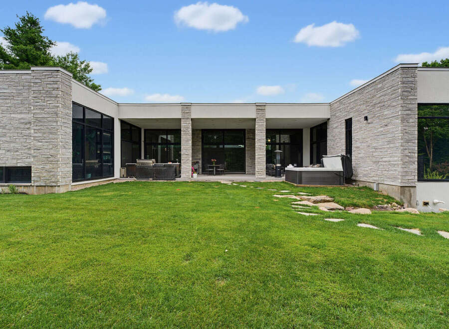 Experience modern luxury with this stunning home featuring a sleek stone facade and expansive glass windows.