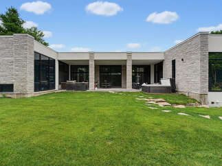 Experience modern luxury with this stunning home featuring a sleek stone facade and expansive glass windows.