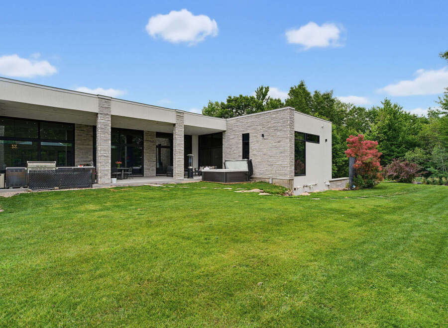 Experience luxury living in this modern architectural masterpiece, featuring expansive glass windows and sleek stone accents.