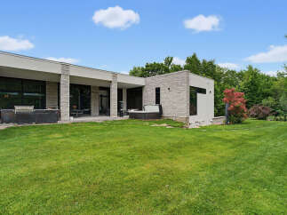 Experience luxury living in this modern architectural masterpiece, featuring expansive glass windows and sleek stone accents.