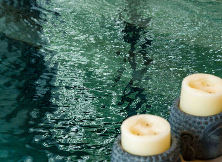Experience ultimate relaxation with this serene spa-like setting, featuring a tranquil pool and calming Buddha-head candle holders.