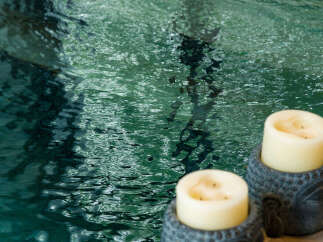 Experience ultimate relaxation with this serene spa-like setting, featuring a tranquil pool and calming Buddha-head candle holders.