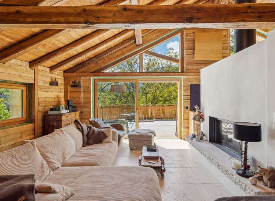 Experience rustic luxury in this stunning wooden chalet, featuring a spacious living area with a cozy sectional sofa and a modern fireplace.
