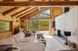 Experience rustic luxury in this stunning wooden chalet, featuring a spacious living area with a cozy sectional sofa and a modern fireplace.