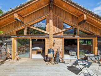 Experience rustic charm in this stunning wooden chalet, featuring expansive glass doors that open onto a spacious deck.