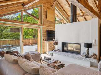 Experience the ultimate alpine retreat in this stunning living room, featuring a modern fireplace and expansive windows that flood the space with natural light.