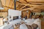 Experience rustic charm in this spacious living area, featuring a striking white fireplace as the focal point and exposed wooden beams overhead.