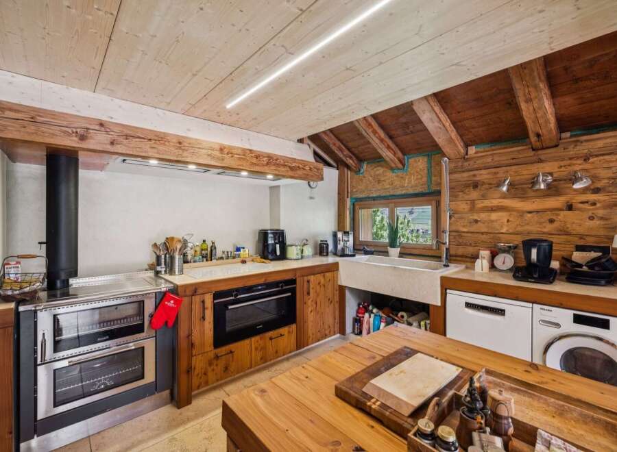 Experience rustic charm in this mountain kitchen, featuring a traditional wood-burning stove and a modern built-in oven.