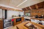 Experience rustic charm in this mountain kitchen, featuring a traditional wood-burning stove and a modern built-in oven.