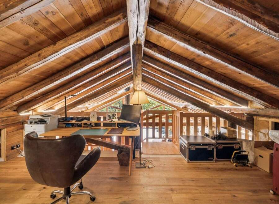 Discover this unique attic workspace, featuring exposed wooden beams and a rustic charm.