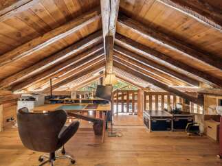 Discover this unique attic workspace, featuring exposed wooden beams and a rustic charm.