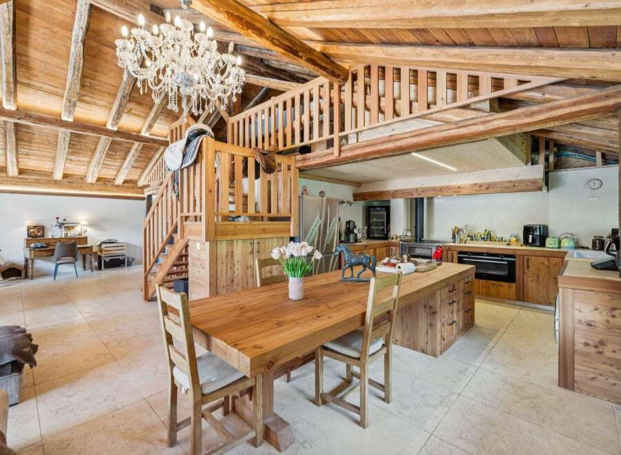 Experience rustic charm in this stunning open-plan living space, featuring a grand wooden dining table and a modern kitchen island.