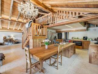 Experience rustic charm in this stunning open-plan living space, featuring a grand wooden dining table and a modern kitchen island.