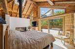 Experience rustic luxury in this stunning mountain retreat, featuring a cozy bedroom with a modern fireplace and a large, open-concept living space.