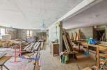 This unfinished concrete space offers a blank canvas for renovation, featuring exposed stone walls and wooden beams.