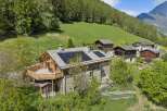 Experience sustainable living in this charming alpine home, featuring a modern roof with solar panels and a spacious wooden deck perfect for enjoying the mountain views.