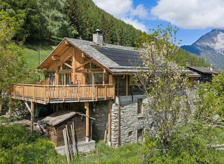 Experience rustic charm in this stunning wooden and stone mountain chalet, featuring a spacious wooden deck perfect for enjoying breathtaking alpine views.