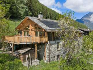 Experience rustic charm in this stunning wooden and stone mountain chalet, featuring a spacious wooden deck perfect for enjoying breathtaking alpine views.