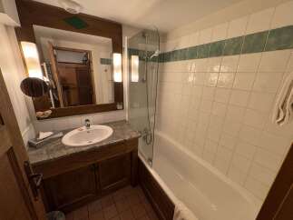 This charming bathroom features a spacious vanity with a granite countertop and a large wooden-framed mirror, perfect for your morning routine.