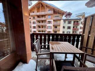 Enjoy breathtaking mountain views from this charming balcony, complete with a rustic wooden table and chairs, perfect for morning coffee or evening relaxation.