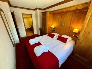 Experience ultimate comfort in this charming hotel room, featuring a plush king-size bed adorned with crisp white linens and vibrant red accents.